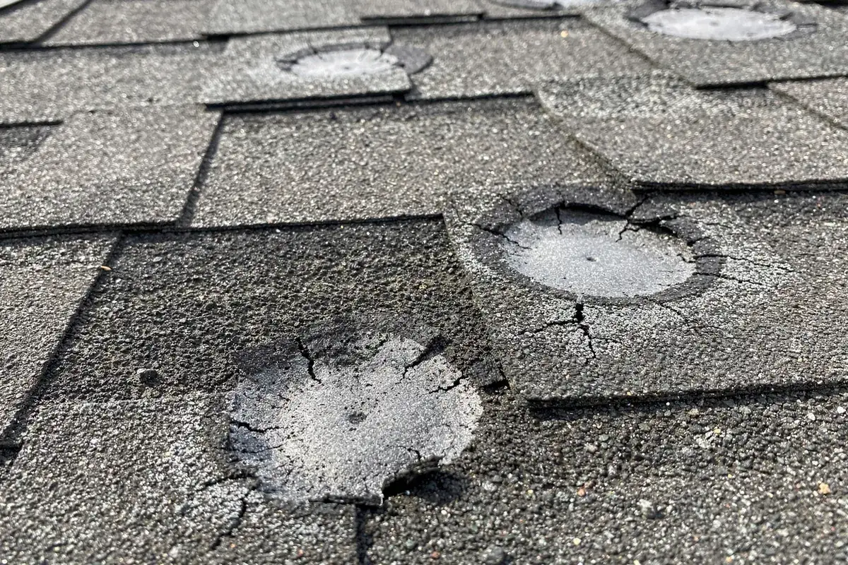 Close up of hail bruising on a charcoal asphalt shingle roof