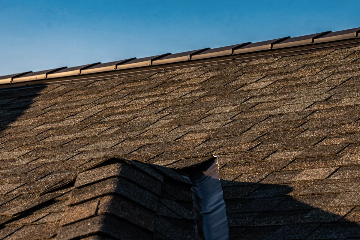 A finished charcoal shingle roof with a ridge vent along the peak